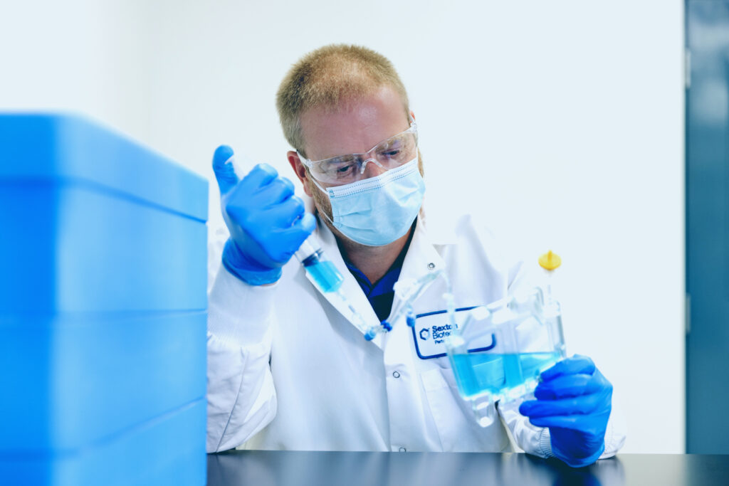 Scientist with blue gloves filling a CellSeal CryoCase with blue liquid from a pipet