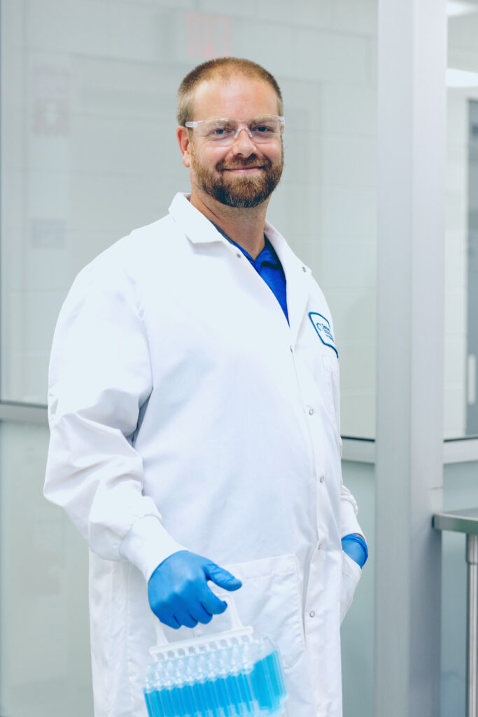 Scientist with blue gloves carrying a bundle of filled CellSeal CryoCases containing blue liquid in the laboratory.
