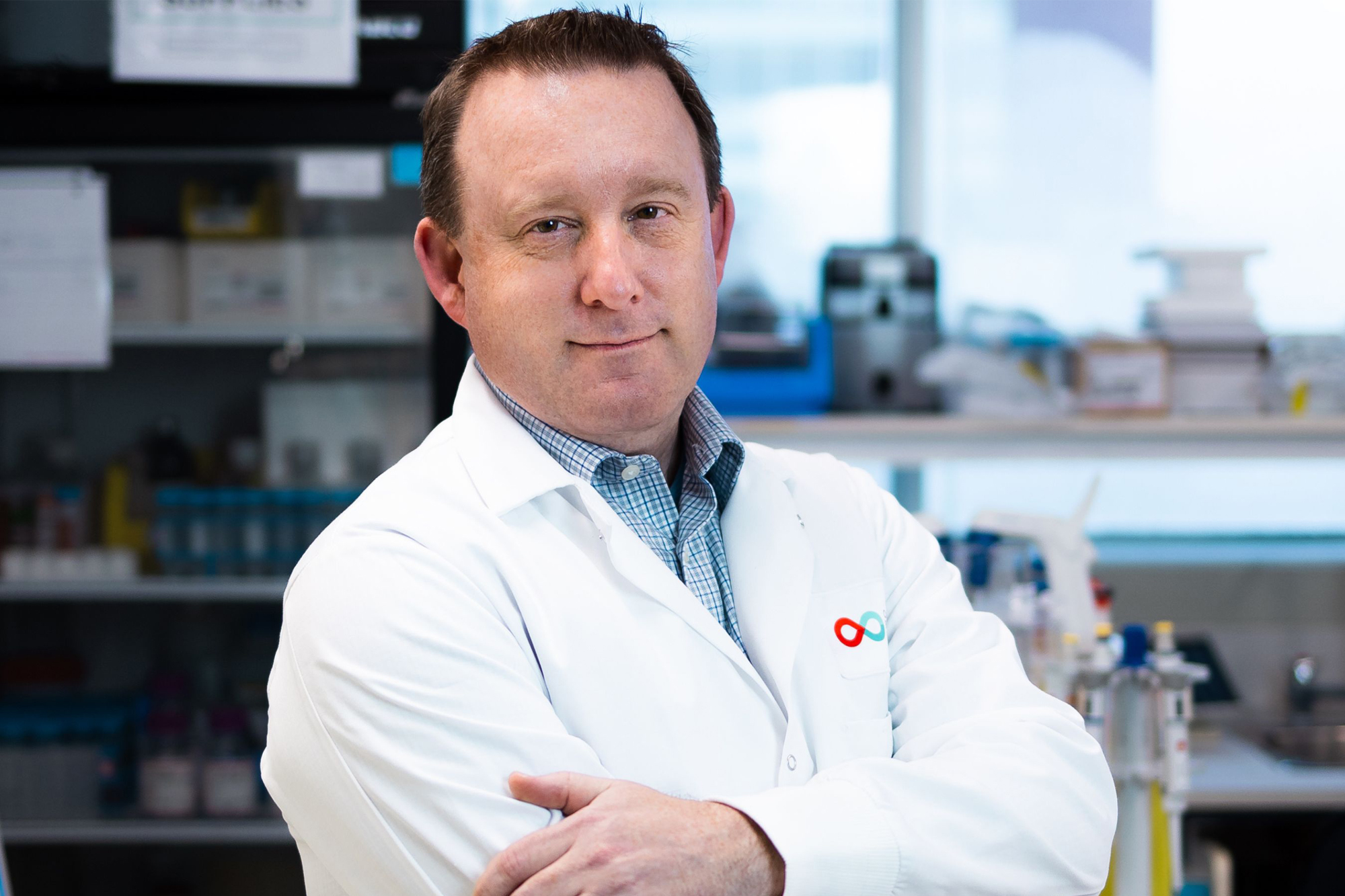 Dr. Jason Acker standing in a laboratory wearing a white lab coat, representing leadership in cryobiology and biopreservation research for cell and gene therapy applications.